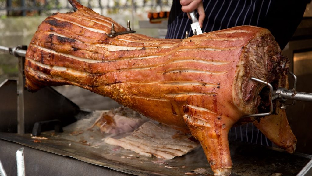 Spit Braai Pretoria - whole pig roasting on a spit braai and being carved at an outdoor function Spit Braai Pretoria - whole pig roasting on a spit braai and being carved at an outdoor function